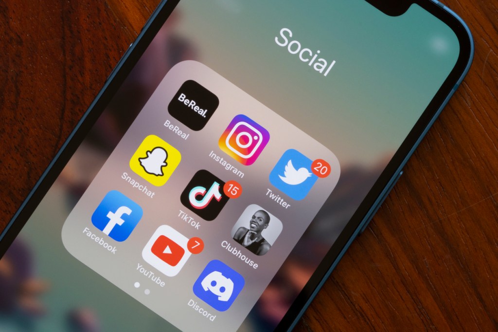 iPhone screen displaying various social media app icons, including BeReal, Instagram, Twitter, Snapchat, TikTok, Facebook, YouTube, and Discord.