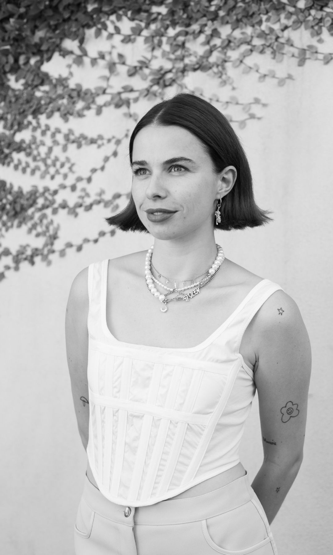Hello! Fashions Fashion and Accessories Writer Orion Scott poses for her headshot in a white corset, trousers and a stack of necklaces